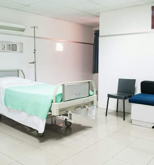 Uma sala de atendimento médico com uma maca, uma cadeira e alguns equipamentos médicos, para representar quanto custa atendimento médico no exterior