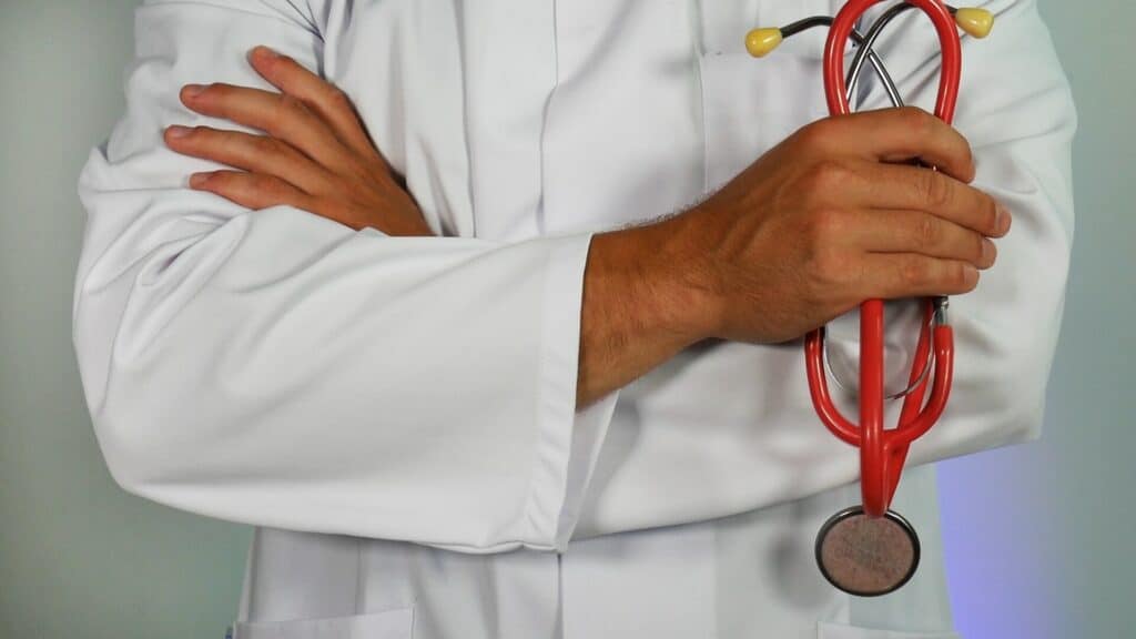 Um homem usando um jaleco médico e segurando um estetoscópio em uma das mãos