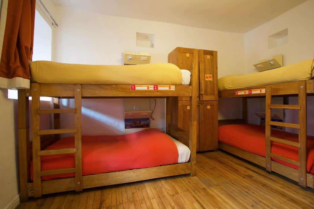 dormitório do pariwana hostel cusco com quatro camas de solteiro em beliche e um pequeno armário com quatro portas.