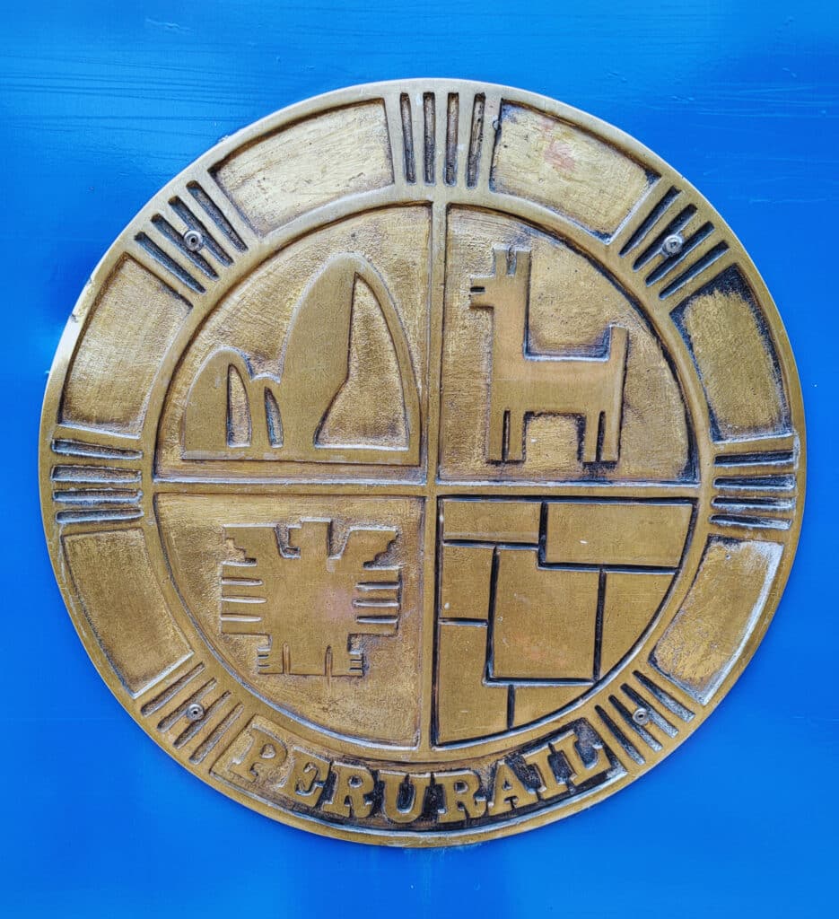 símbolo da perurail: um círculo divido em quatro, em cada uma das partes há um desenho. Montanhas, uma lhama, um condor e um desenho de campos de agricultura