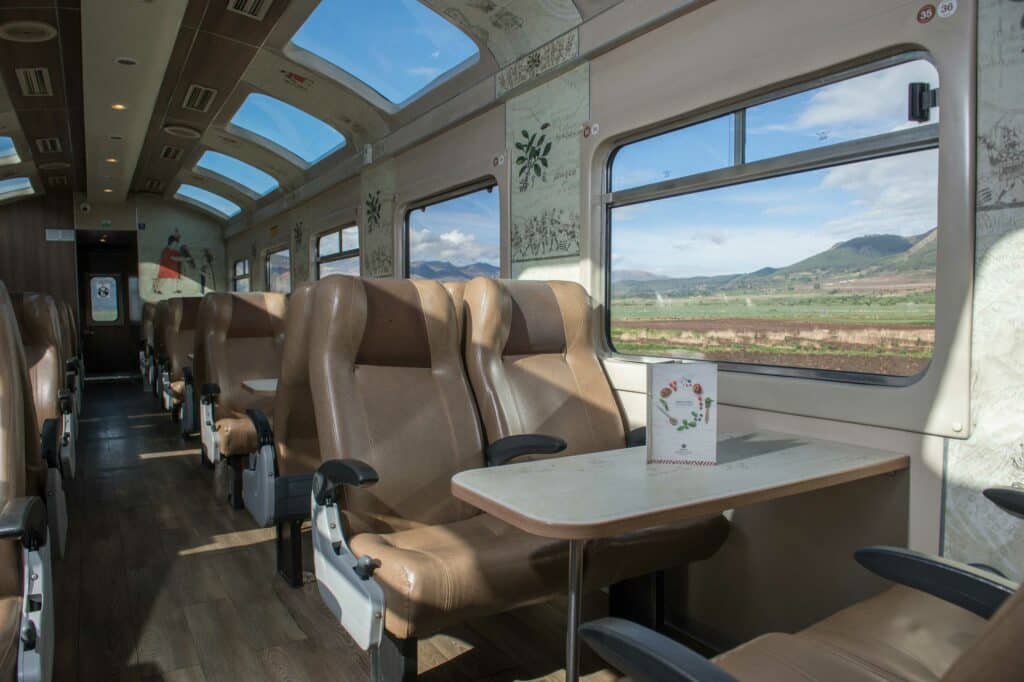 vagão do trem Expedition da Peru Rail mostrando as poltronas de couro ao lado de janelas com vista para a paisagem do lado de fora