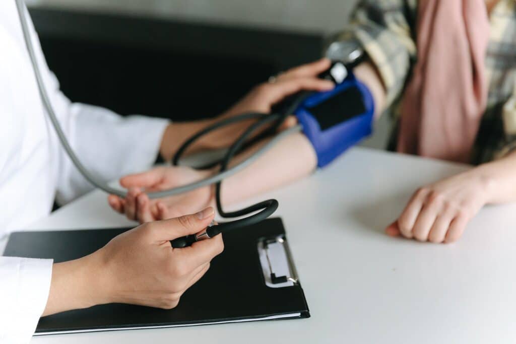 Uma médica tirando a pressão usando um aprelho preso ao braço da uma paciente