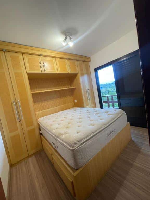 Foto do quarto em Piemonte Flat Serra Neg SP. Há uma cama box de casal no centro, e ao redor dela há um guarda-roupa planejado que vai até o teto. Do lado direito há uma porta preta com varanda.
Ilustra o post sobre airbnb em Serra Negra.