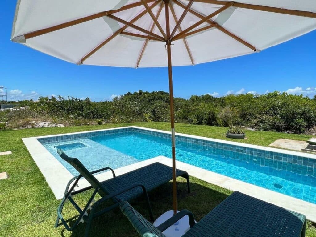 Vista da piscina da Casa da Laguna – Costa do Sauipe durante o dia com cadeiras a frente e ao fundo a piscina.