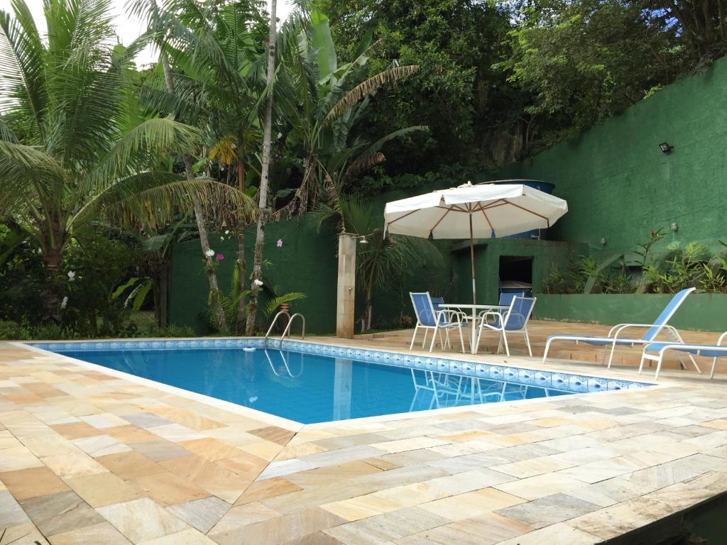 Piscina da Casa Praia de Santiago durante o dia com piscina ao centro e do lado esquerdo cadeiras com mesas.