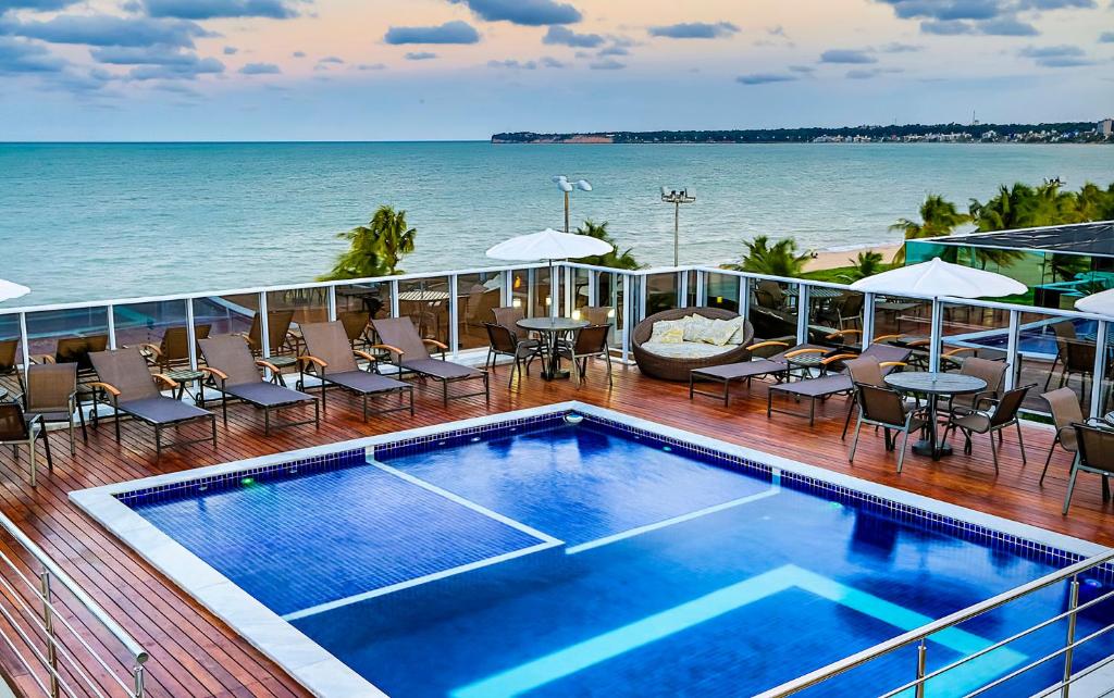 Piscina do Laguna Praia Hotel na cobertura do hotel com vista direta para o mar, há um deck ao redor com espreguiçadeiras, mesas, cadeiras e guarda-sóis, para representar tudo sobre a Paraíba