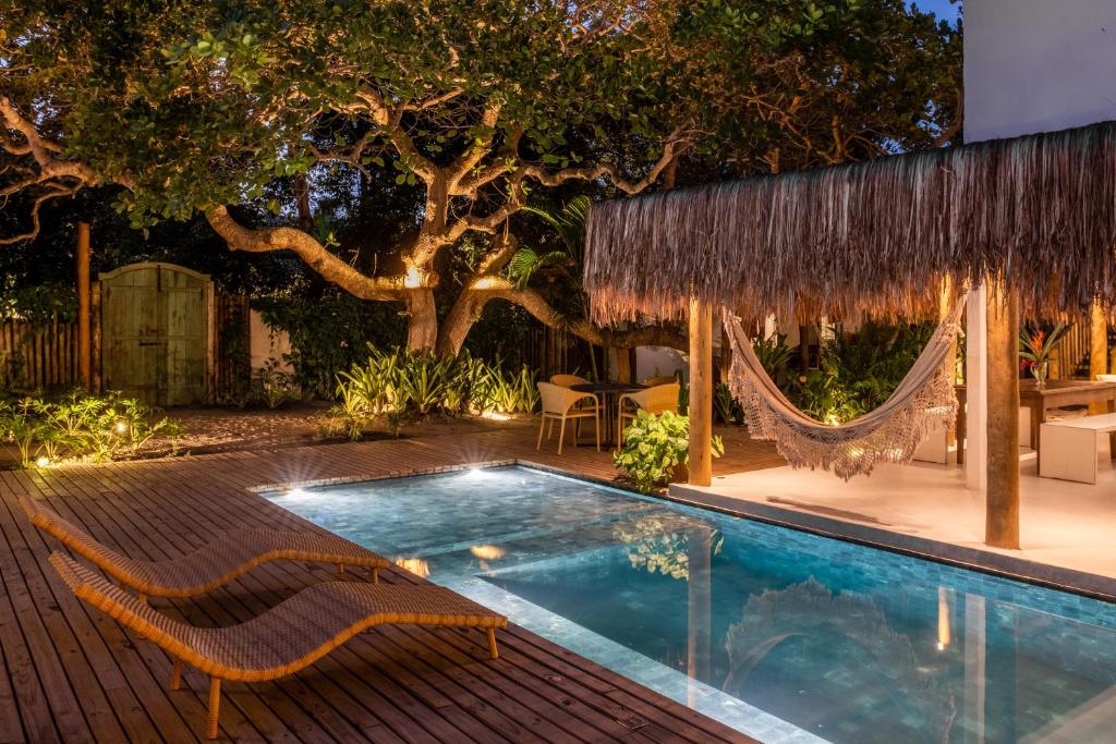 Imagem da piscina ao ar livre da Vila Florir no final do dia com cadeiras do lado esquerdo da imagem e em frente a elas uma piscina e do lado esquerdo da piscina a estadia.