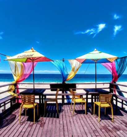 Deck na praia da Pousada Potigua para ilustrar post sobre pousadas em Maricá. Com cadeiras, mesas e guarda-sóis.