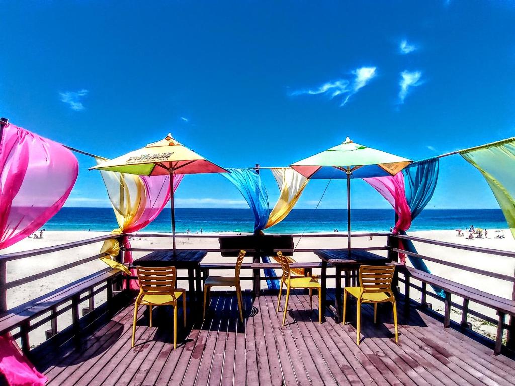 Deck na praia da Pousada Potigua para ilustrar post sobre pousadas em Maricá. Com cadeiras, mesas e guarda-sóis.