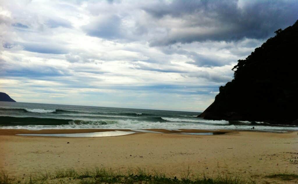 Imagem da Praia da Juréia em São Sebastião durante o dia com areia a frente e ao fundo o mar.