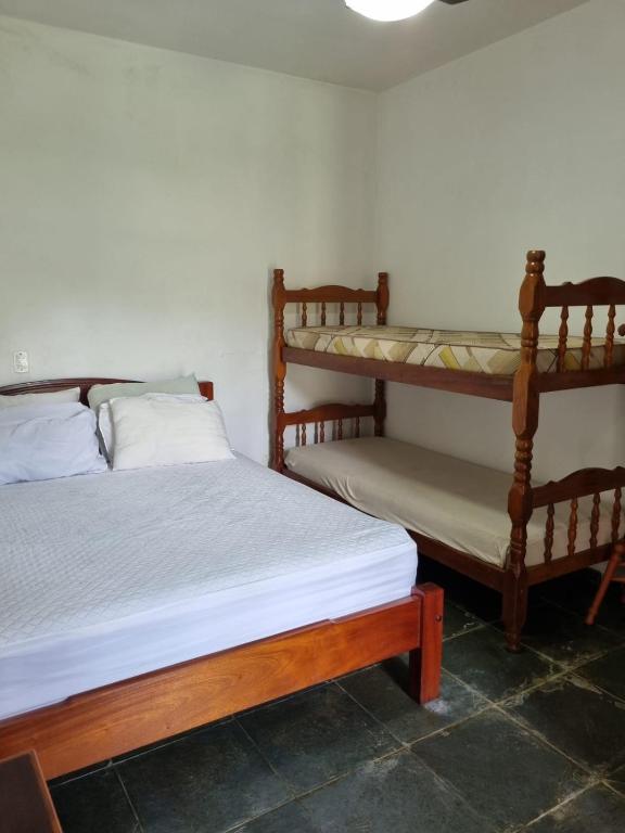 Quarto do Aconchegante Casa de Temporada com cama de casal do lado direito da imagem e do lado esquerdo da cama de casal uma cama de beliche. Representa airbnb na praia da Lagoinha.