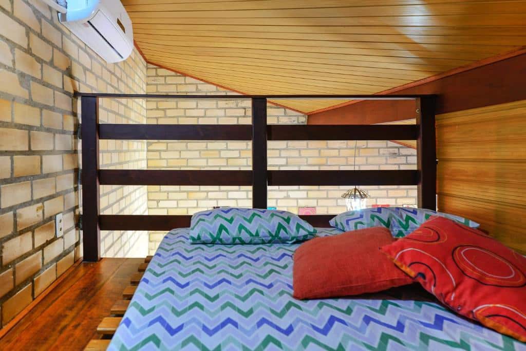 Quarto do airbnb Adora Suites. A cama está no canto direito do quarto e o teto do quarto é bem baixo. Imagem para ilustrar o post airbnb em Ilha Grande.
