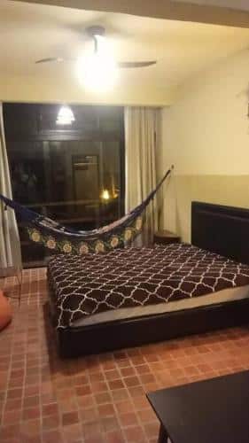 Quarto do Altar da praia Vermelha 180° de vista para o mar com cama de casal do lado direito da imagem com uma rede do lado esquerdo pendurada. Representa airbnb na praia do Tenório.