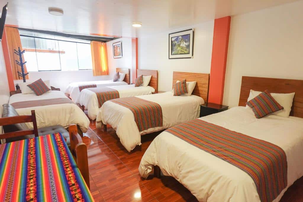 quarto de família com cinco camas de solteiro, além de uma pequena mesa para trabalho no canto inferior esquerdo da foto.