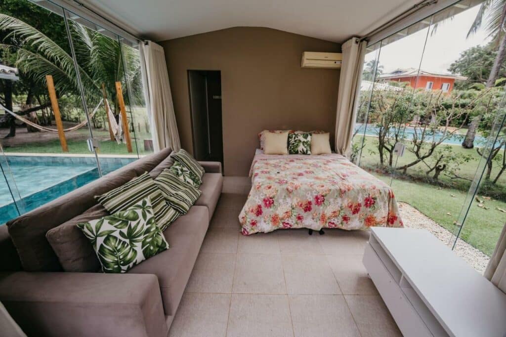 Quarto do Beach House Sauípe com sofá do lado esquerdo da imagem, do lado direito ao fundo uma cama de casal. Representa airbnb na Costa do Sauípe