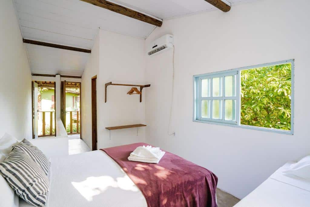 Quarto da Casa da Esquina Caraíva com cama de casal do lado esquerdo da imagem no centro do quarto e do lado direito da cama uma cama de solteiro. Representa airbnb em Caraíva.