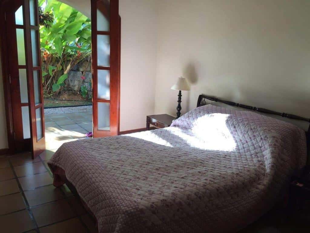 Quarto da  Casa de Praia a 80 metros da Praia em Ubatuba  com cama de casal do lado direito da imagem do lado direito da cama uma cômoda com luminária. Representa airbnb na praia do Tenório.