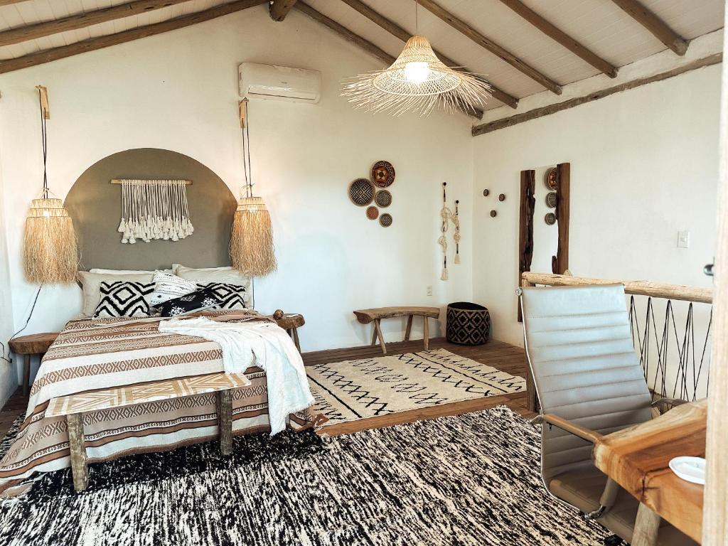 Quarto da Casa Mundi com cuma mesa de madeira do lado direito da imagem no canto, do lado esquerdo da imagem ao fundo uma cama de casal com uma cômoda em cada lado da cama. Representa airbnb em Caraíva.