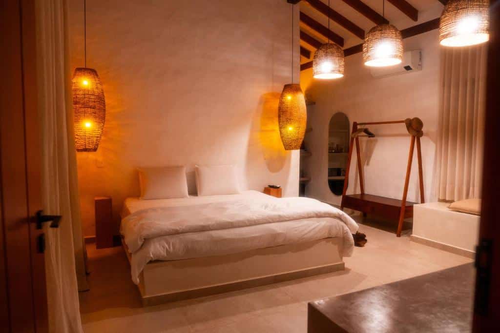 Quarto do Nai com cama de casal no centro do quarto e em cada lado da cama uma luminária pendurada no teto em cada lado. Representa airbnb na praia de Santiago.
