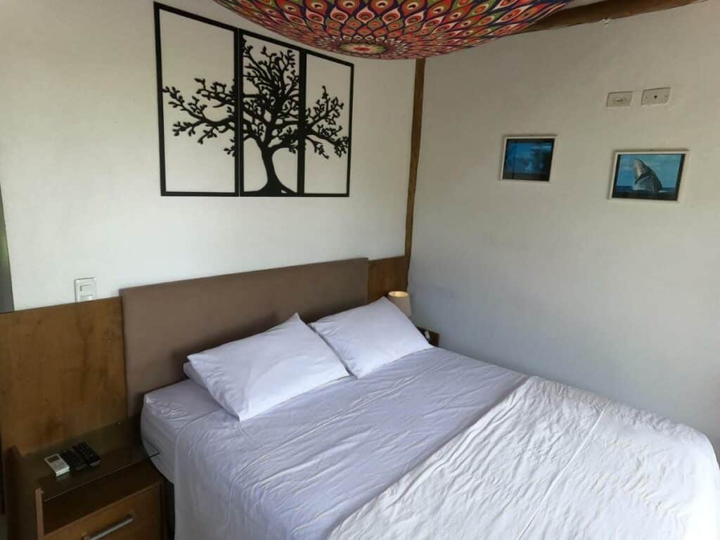 Quarto do Chalé e Suite Manacá com cama de casal do lado esquerdo da imagem. Representa airbnb na praia do Félix.