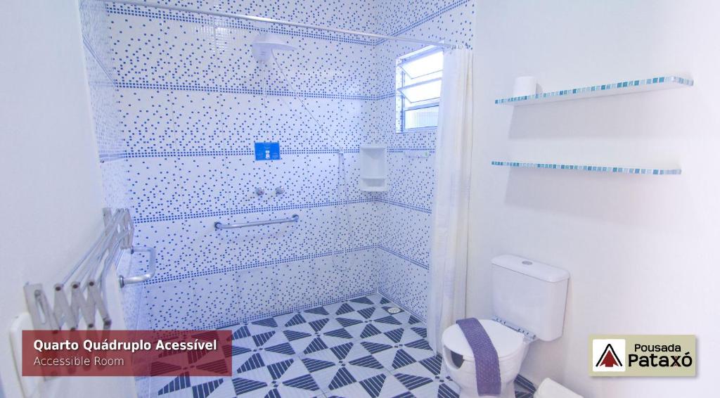 Banheiro com acessibilidade da Pousada Pataxó com vaso sanitário do lado esquerdo da imagem a frente, e ao fundo área do banho com barra de apoio.