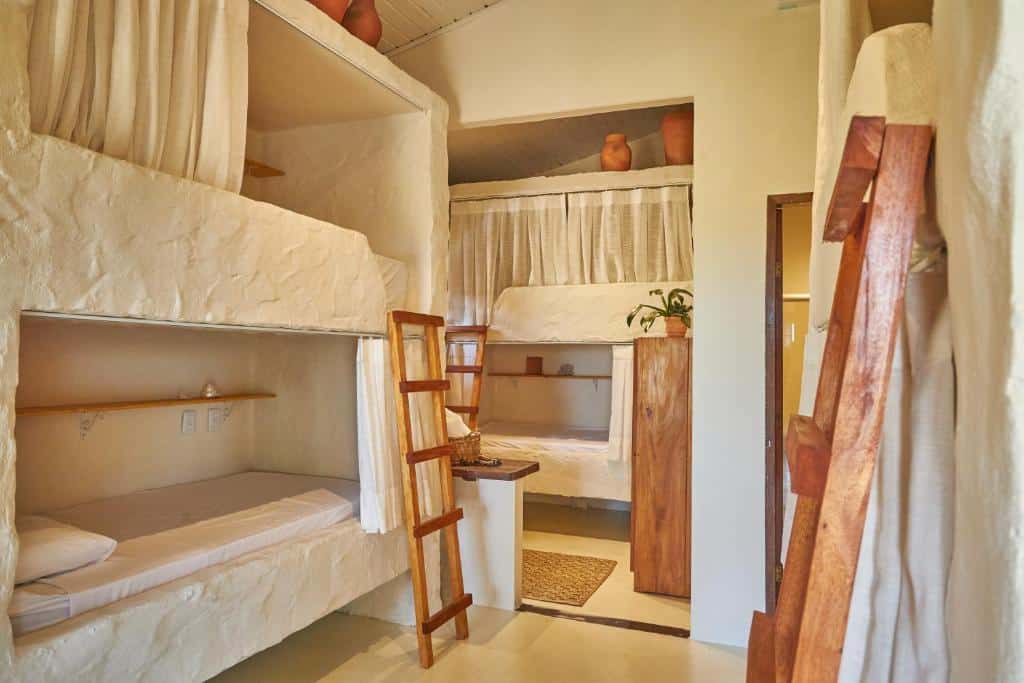 Quarto compartilhado do Evoé Pousada Hostel Caraíva com uma cama beliche do lado esquerdo da imagem e ao fundo outra cama de beliche.