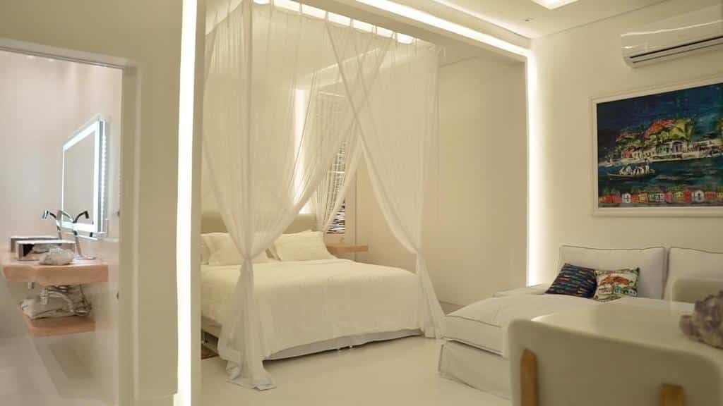 Quarto da Cristal da Mata – Casa exclusiva e privativa com uma mesa no canto direito da imagem ao fundo um sofá e do lado direito do sofá uma cama de casal. Representa airbnb em Caraíva.