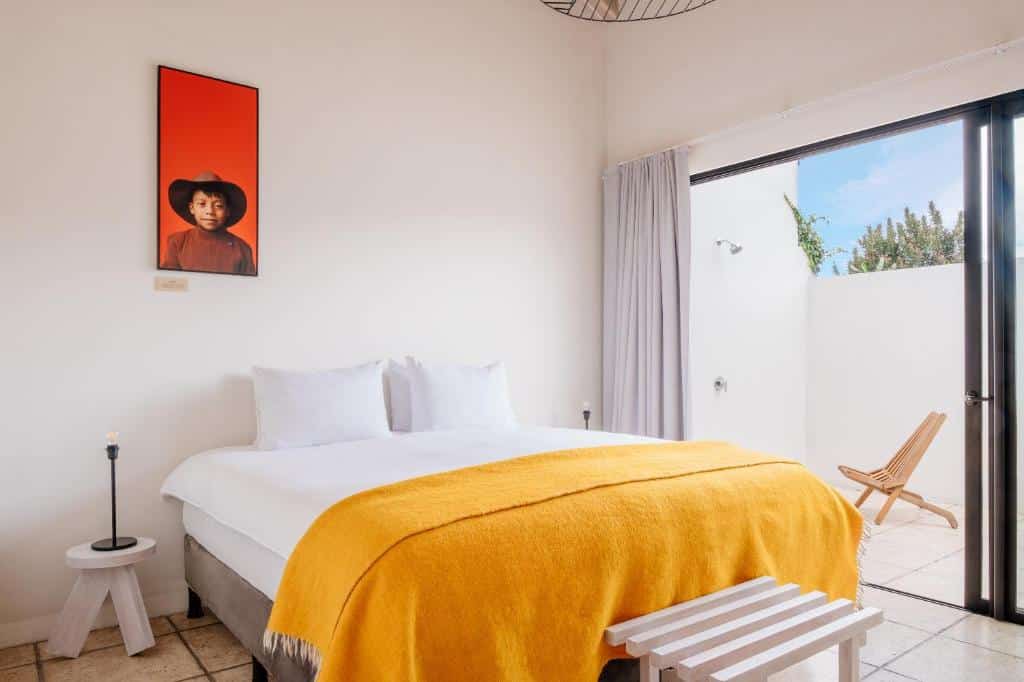 Quarto do Good Hotel Antigua Cobertura com uma cama de casal e uma varanda térrea com uma cadeira, há alguns itens de madeira e um quadro próximo da cama