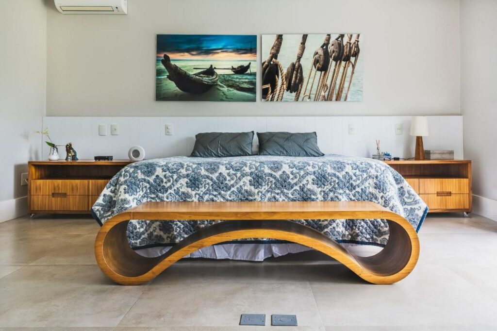 Quarto da Mansão de luxo perto da praia em Caraguatatuba com cama de casal no centro do ambiente com uma cômoda em cada lado da cama e no pé da cama uma cômoda de madeira.