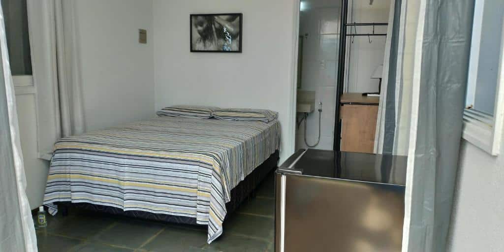 Quarto do Oré Suítes e Chalés com cama de casal do lado esquerdo da imagem do lado direito a frente um frigobar. Representa airbnb na praia do Tenório.