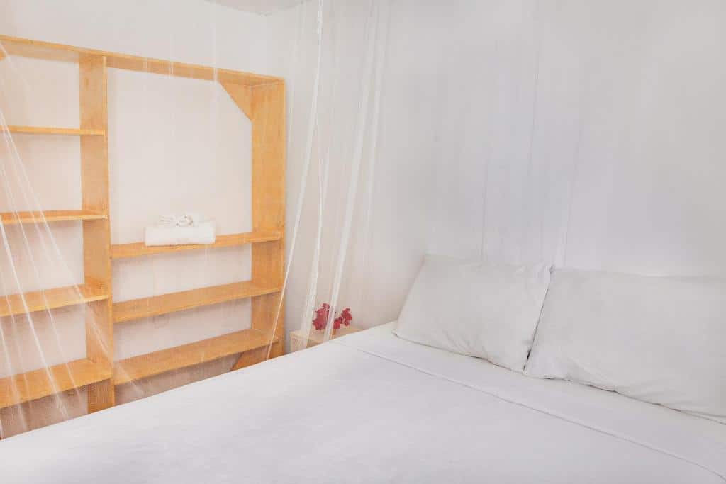 Quarto da Pousada Do Guga com cama de casal do lado direito da imagem, do lado direito da cama uma cômoda e uma armário de madeira. Representa airbnb em Caraíva.