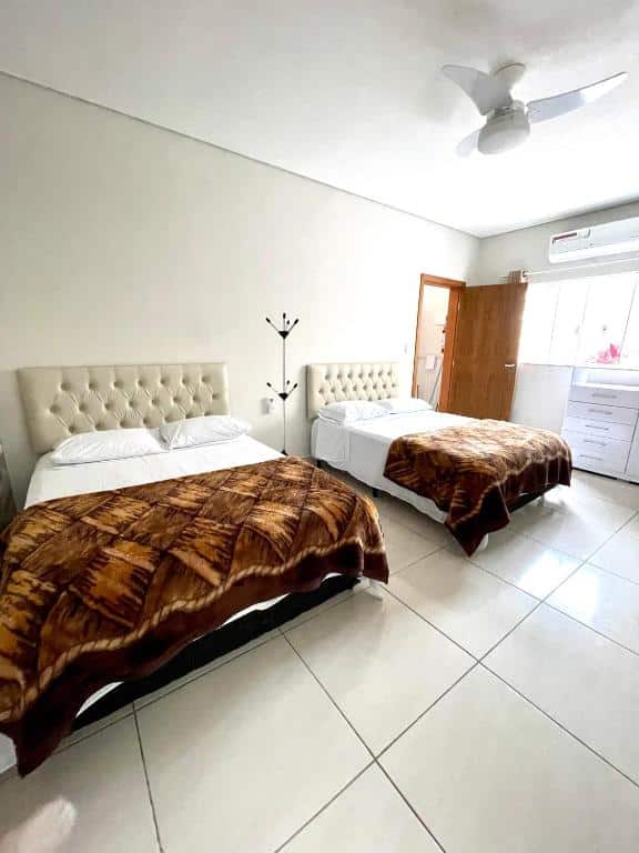 Quarto do Recanto da Ivete com uma cama de casal do lado esquerdo da imagem e outra cama de casal do lado direito. Representa airbnb na praia da Juréia.
