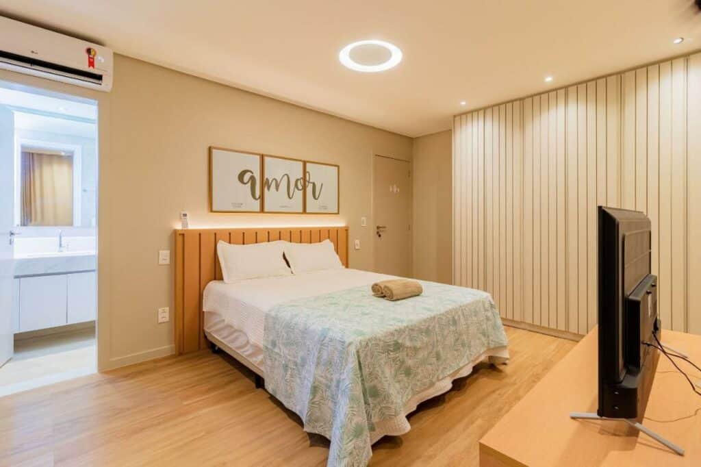 Quarto da SA05 Excelente Casa 5 Suítes – Condomínio Reserva de Sauípe com cama de casal do lado esquerdo da imagem no centro em frente a cama uma comoda com TV. Representa airbnb na Costa do Sauípe