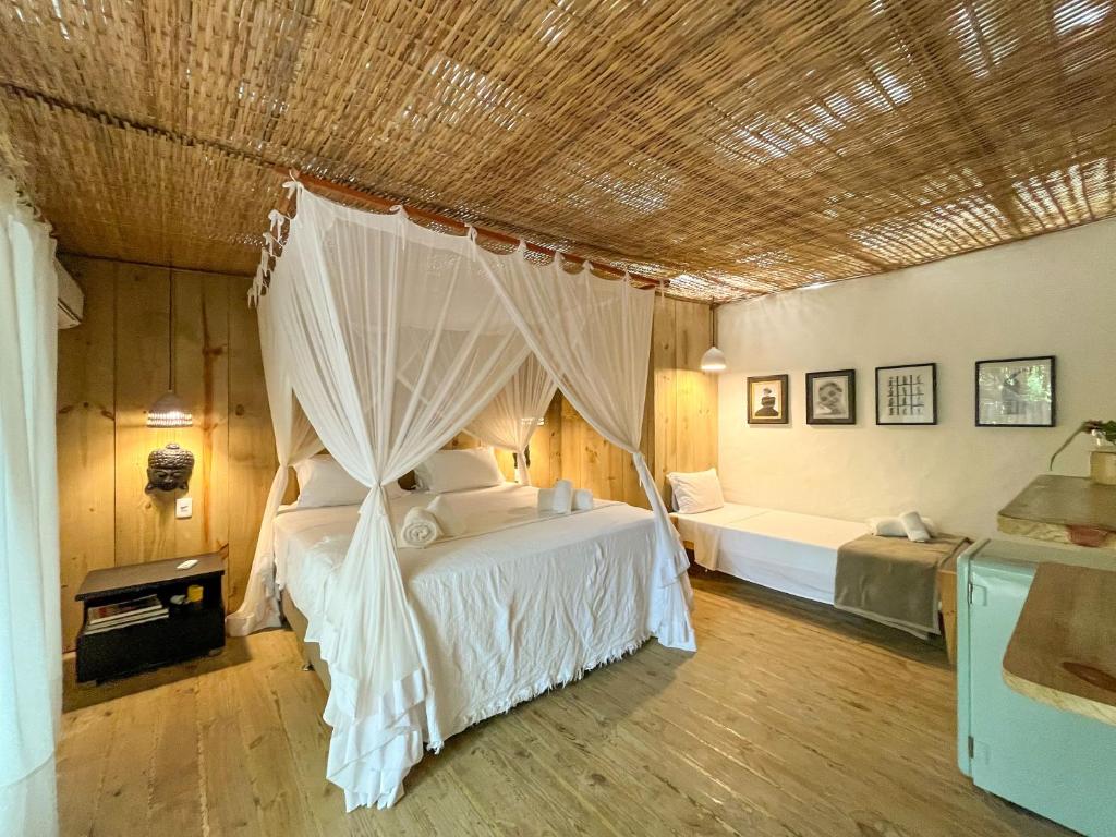 Quarto da Vila Botanika Caraíva com cama de casal do lado esquerdo da imagem no centro do quarto e do lado esquerdo da cama de casal uma cama de solteiro. Representa airbnb em Caraíva.