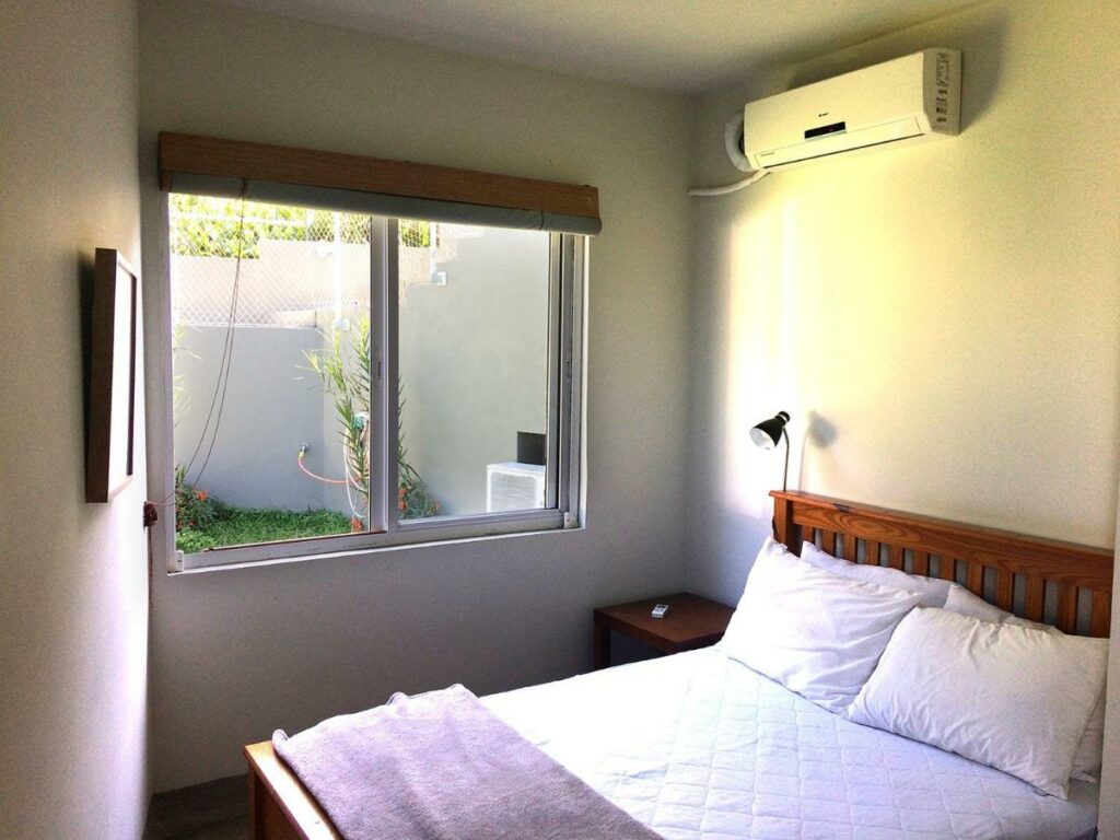 Quarto da Vila Praiana com cama de casal no lado esquerdo da imagem na frente do lado direito uma cômoda. Representa airbnb na praia da Lagoinha.