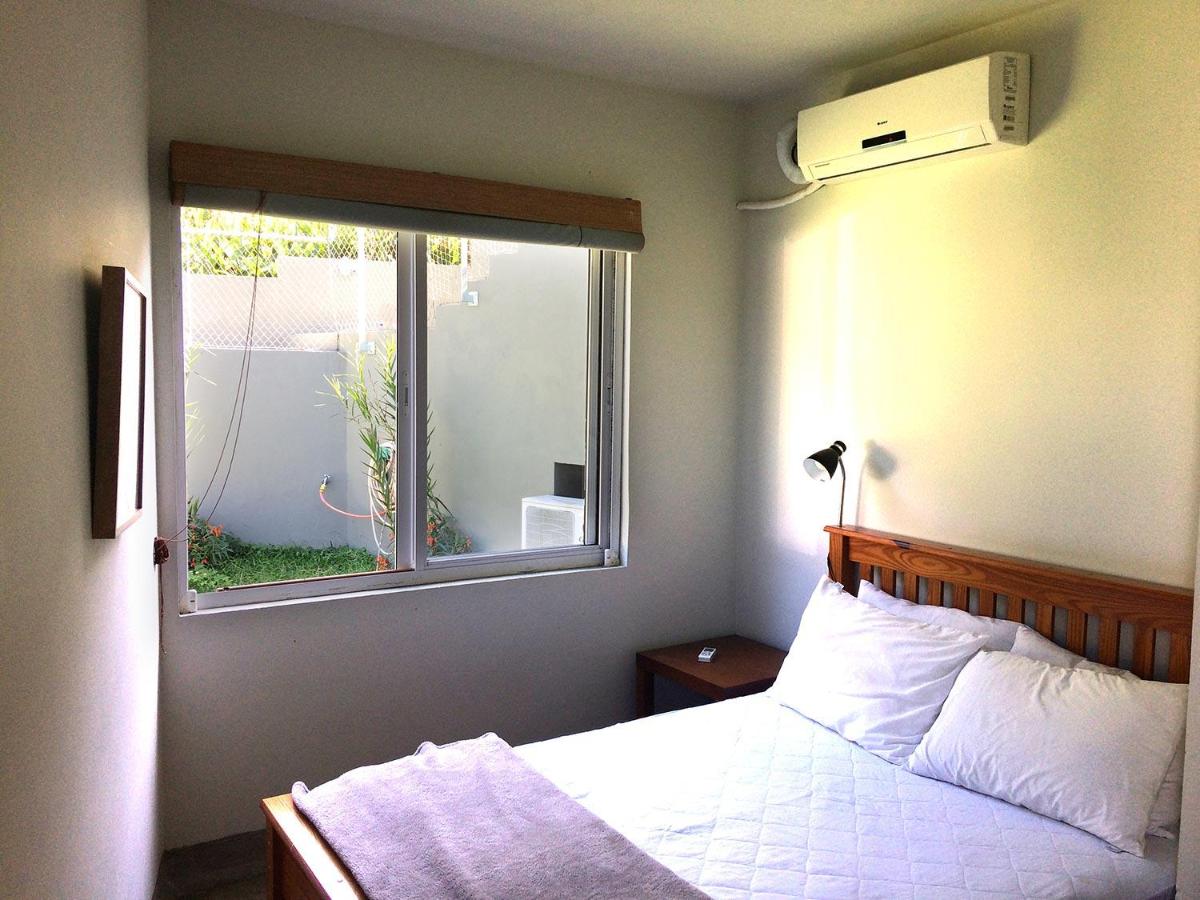 Quarto da Vila Praiana com cama de casal no lado esquerdo da imagem na frente do lado direito uma cômoda.