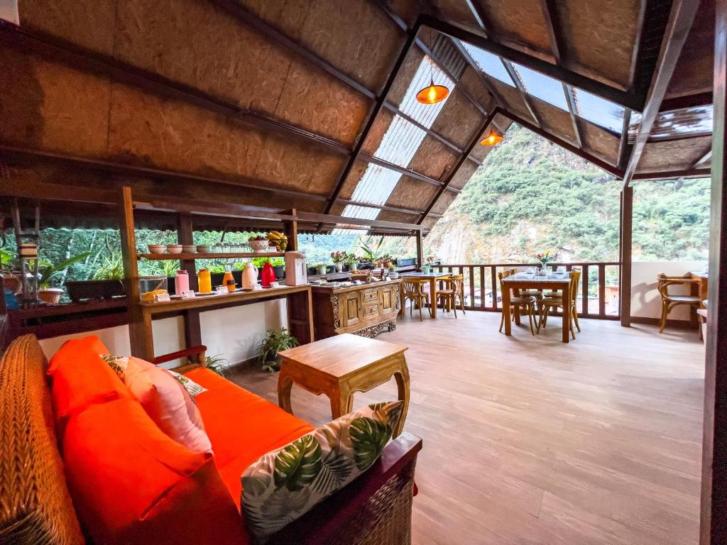 área de refeição do rupa rupa high jungle bed and breakfast com teto alto em vigas de madeira, móveis de madeira em estilo rústico e uma bela vista da vegetação ao fundo.