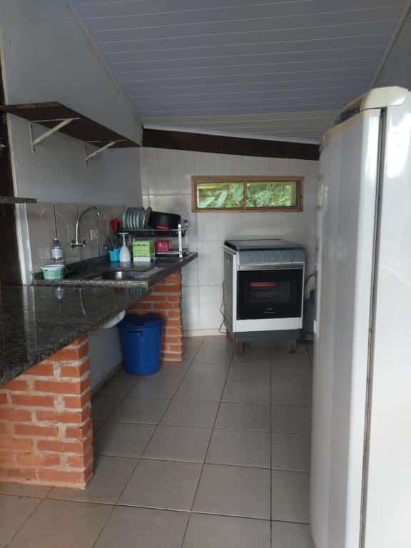 Cozinha do Solaris do Una com bacada com pia e utensílios de cozinha ao lado esquerdo encarando um fogão e uma geladeira.