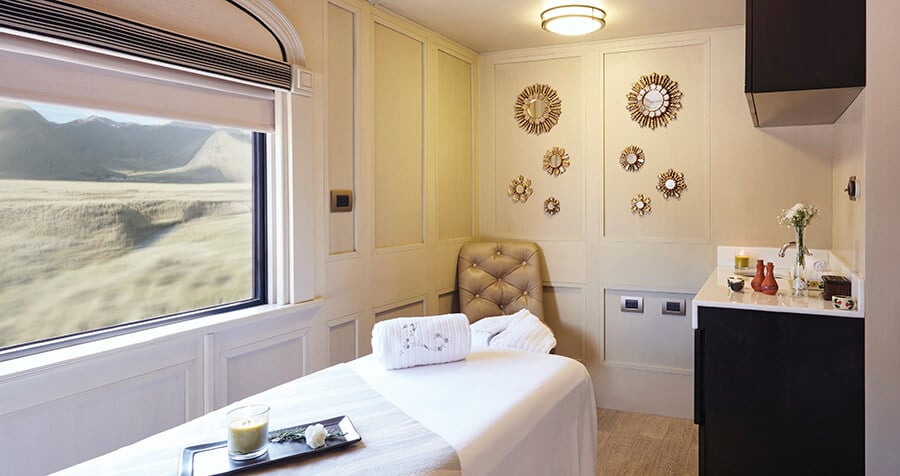 área de SPA do vagão andean explorer perurail com uma maca ao centro, um balcão com pia ao lado direito e uma ampla janela à esquerda