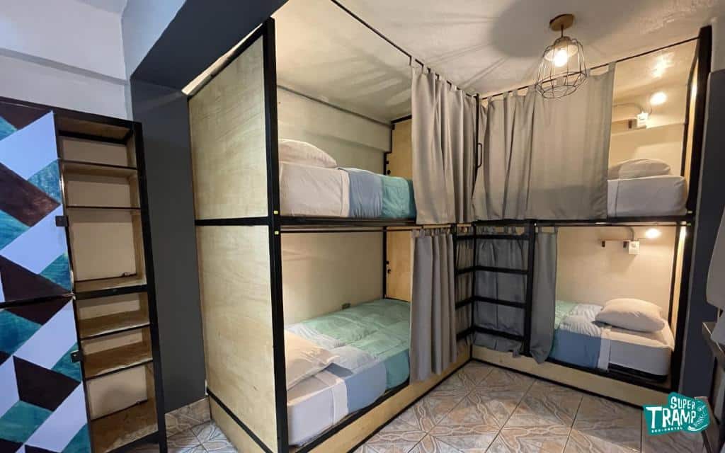 dormitório do Supertramp Hostel com quatro camas em beliches fechados e separados por cortinas e finas paredes de tablado.