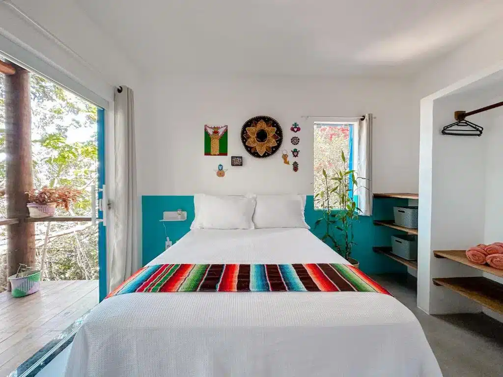 Quarto do Vila Real Apartamentos. Vemos a cama e frente, no centro da foto, essa que é box e de casala. Na esquerda há uma varanda, e à direita há prateleiras que servem para guardar toalhas, roupas, etc.