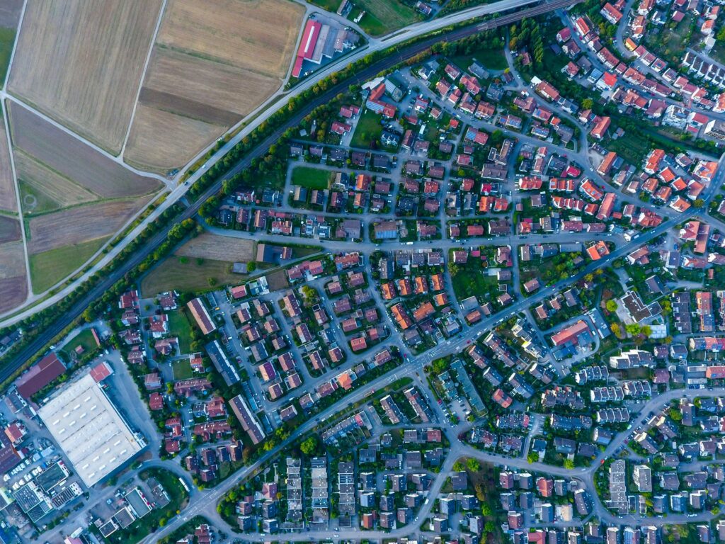 vista aérea da cidade de 
Ehningen, na Alemanha, com várias casinhas pequeninas em ruas desenhadas e, do outro lado de uma rodovia, campos grandes de plantações, para ilustrar o post de Seguro Viagem LATAM