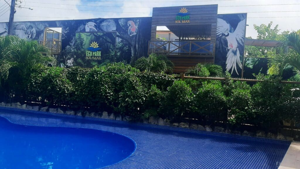 Frente do Zoológico Ecopark, com uma piscina e uma fileira de arbustos atrás e a entrada do zoológico atrás. Representa o que fazer em Maragogi