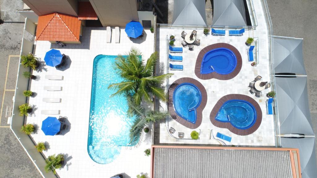 Imagem aérea do Aguas do Iguaçu Hotel Centro que mostra do lado direito três piscinas com algumas espreguiçadeiras em volta e do lado direito uma piscina maior com alguma árvores e espreguiçadeiras e guarda-sóis em volta. Imagem ilustrando post Hotéis em Foz do Iguaçu.