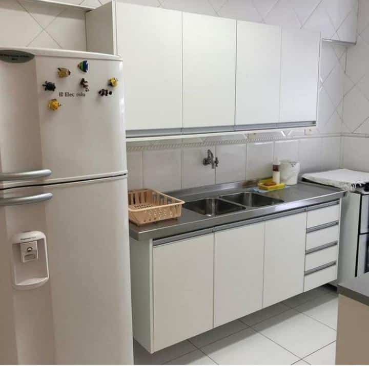 Cozinha com geladeira, pia, armários e fogão no Apartamento na Praia de Pitangueiras-Guarujá.