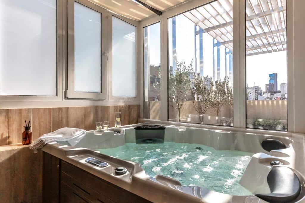 banheira de hidromassagem com vista do exterior, em que entram raios de luz nas paredes de vidro no Huinid Obelisco Hotel, um dos hotéis de luxo em Buenos Aires
