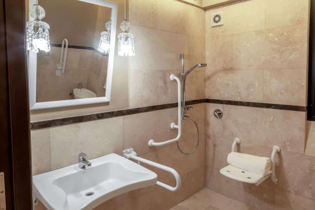 banheiro com adaptações no Esplendor by Wyndham Buenos Aires Tango, com diversas barras de apoio, cadeira de banho, chuveirinho e pia mais baixa e aberta para facilitar o acesso