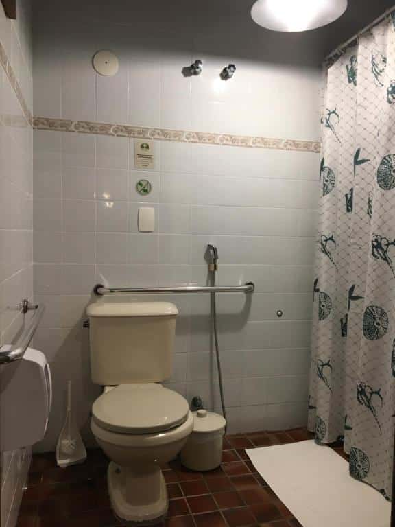 Banheiro da Pousada Aroeira com vaso e barras de segurança.