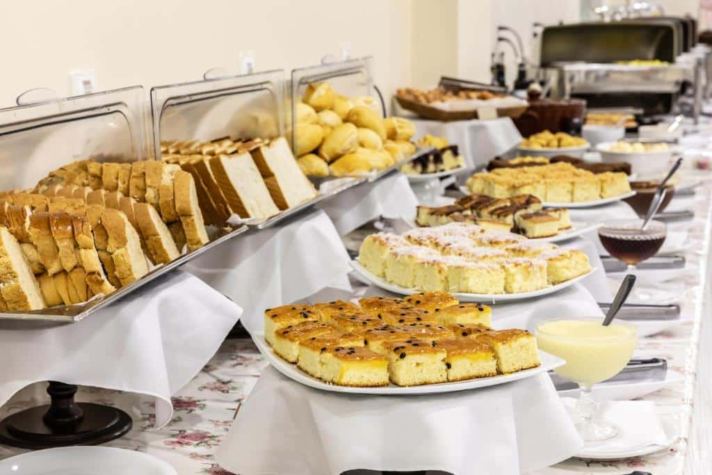 Foto do Bogari Hotel, mostrando uma mesa com vários alimentos e molhos, como pães, bolos, doces, etc.