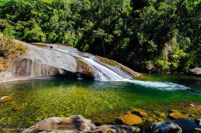 Imagem tirada de dia da Cachoeira do Escorrega, em Visconde do Mauá. No fundo há várias árvores.